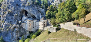 Schloss Predjama, Sloweniens spektakuläre Felsenburg vom Tal aus gesehen bei strahlendem Wetter