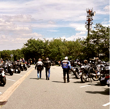 Blick auf den Motorrad-Parkplatz auf dem Köterberg mit zahlreichen Motorrädern und einigen Bikern, die die Maschinen betrachten