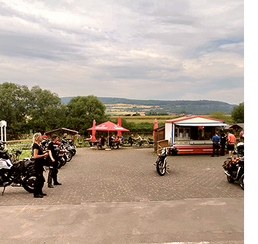 Blick auf den diesmal wenig besuchten Biker-Treffpunkt Reileifzen mit den Meer Bikerinnen Anja und Angie auf der linken Seite, mehreren Motorrädern und der Weser im Hintergrund