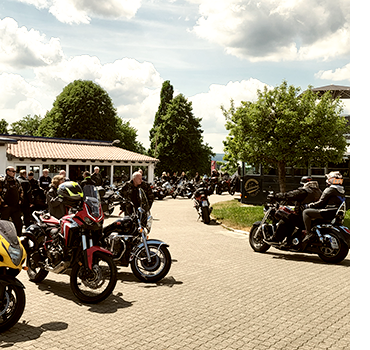 Auf dem Parkplatz vom Bikerpoint Fuchs in Uslar stehen sehr viele Motorräder bei leicht bewölktem Frühlingswetter.